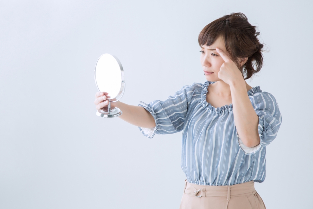 鏡で眉毛を見る女性