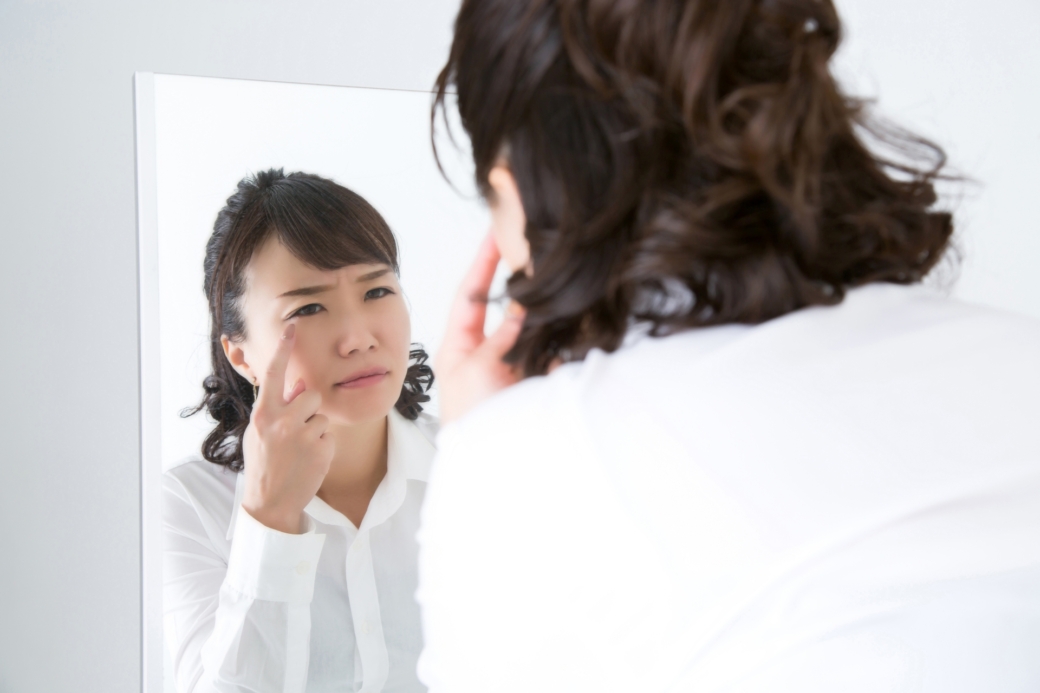 鏡を見て顔をしかめる女性