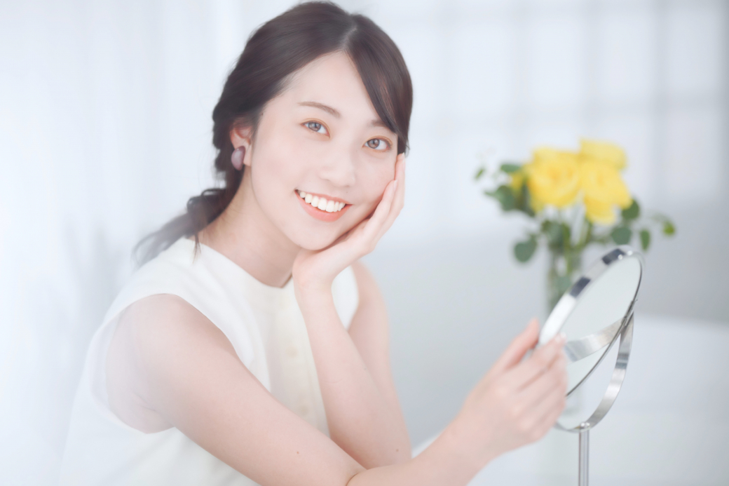 鏡を見ながら頬を触る女性