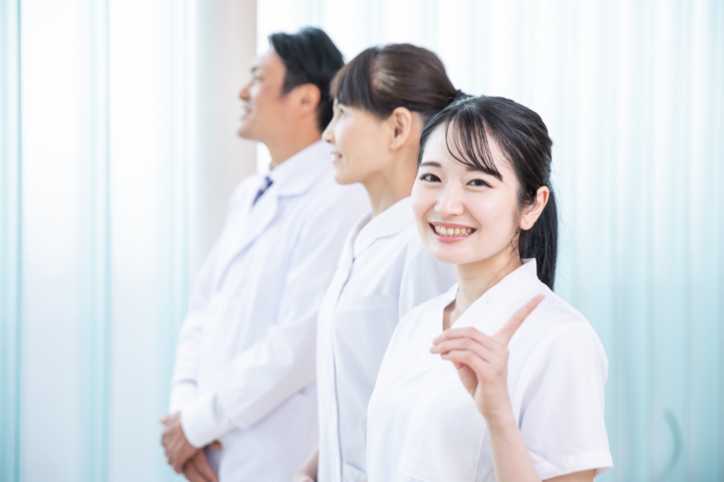 こちらを見てほほ笑む看護師の女性と正面を向いている男性医師と看護師