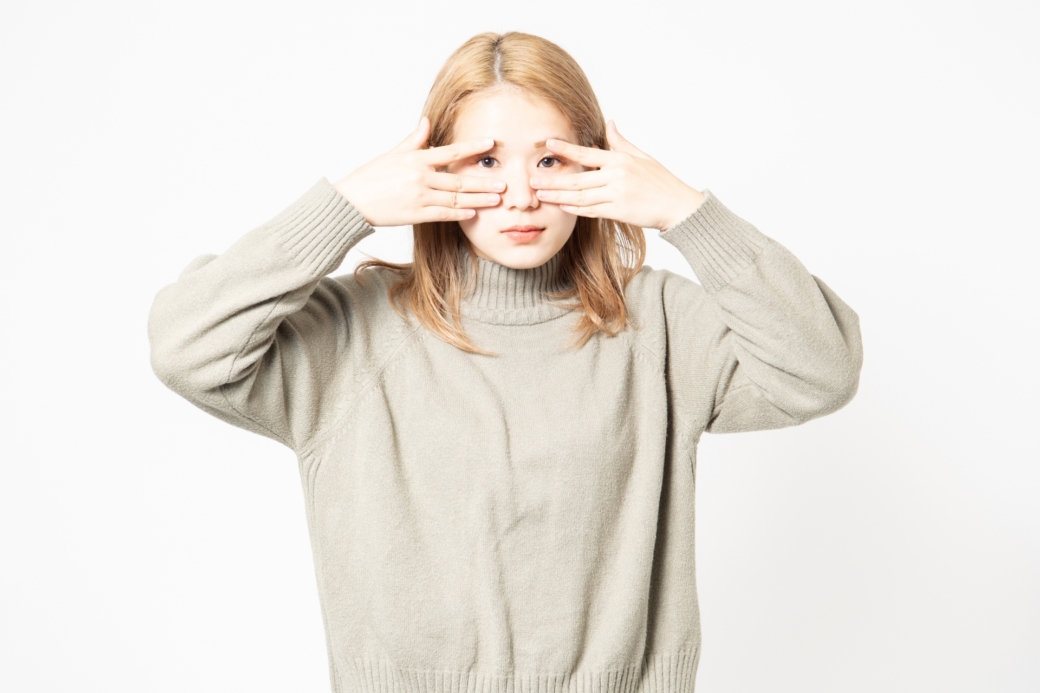 目を隠すセーターを着た若い女性