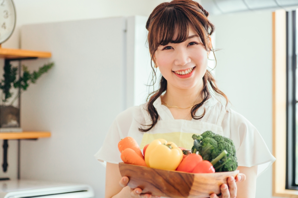 キッチンで野菜を持つ女性（笑顔）