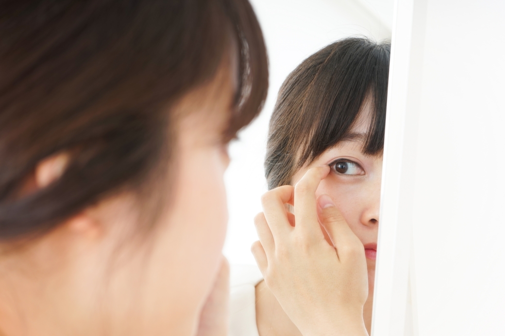 鏡で自分の目をチェックする女性