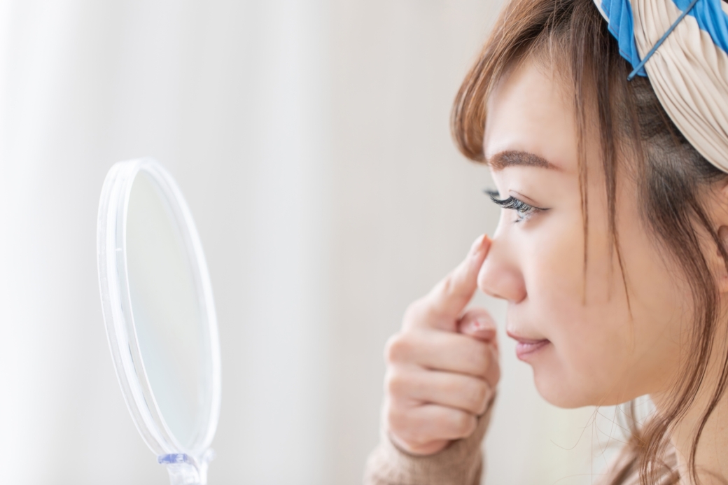 鏡で自分の鼻をチェックする女性