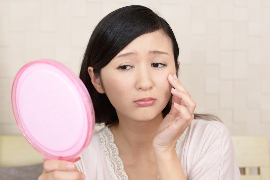 鏡を見て悩む女性